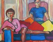 Une femme, goguenarde, en tailleur rose-Chanel, sur un canapé multicolore... Un homme est assis derrière elle dans un fauteuil vieux-rose.